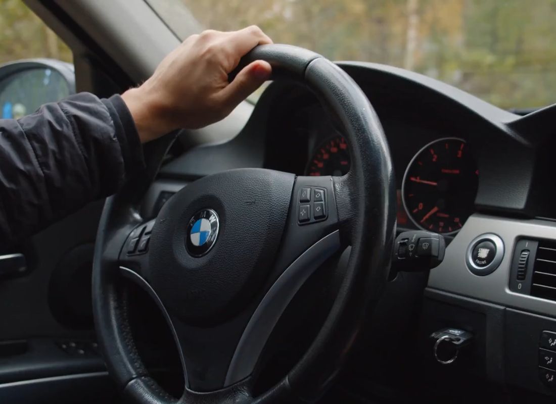 prikaz momka koji drži volan u automobilu jednom rukom